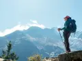 Kobieta z plecakiem i kijkami trekkingowymi podziwia majestatyczne góry w drodze na mount everest base camp.