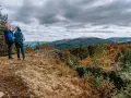 Dwóch turystów na szczycie, kamień i widok na góry. Czas przejścia przez jesienne Bieszczady.