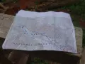 Mapa szlaku grzbietu pacyficznego z zaznaczonymi punktami i rzekami, leżąca na drewnianej ławce.