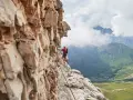 Wspinacz na via ferraty w Dolomitach, z widokiem na kręte drogi w dolinie.