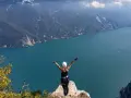 Kobieta w kasku i uprzęży cieszy się widokiem na jezioro Garda po pokonaniu via ferrata.