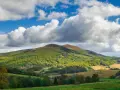 Bieszczady jakie to góry? Łagodne, zielone wzgórza pokryte lasami, z pojedynczymi szczytami i malowniczymi dolinami, pod błękitnym niebem z kłębiastymi chmurami.