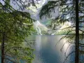 Spokojne Morskie Oko latem, otoczone zielenią drzew i majestatycznymi górami.
