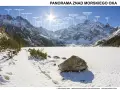 Zimowa panorama Tatr Wysokich z Morskim Okiem w tle. Widoczne szczyty: Rysy, Mięguszowiecki, Mnich. Szlak prowadzi przez zaśnieżony teren.