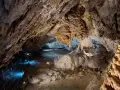 Wnętrze jaskiń w Zakopanem, z naciekami, stalaktytami i stalagmitami, oświetlone niebieskim światłem.