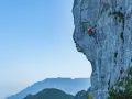 Wspinacz pokonuje via ferrata niemcy, zmagając się z pionową ścianą skalną. W tle piękne góry.