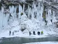 Lodowe wodospady w Rudawce Rymanowskiej zimową porą. Grupa ludzi obserwuje wspinaczkę lodową. Jak dojechać?