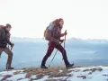 Para, co to jest hiking? To dwójka ludzi z plecakami i kijkami, idących po ośnieżonym szlaku w górach.