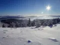 Słońce świeci nad zaśnieżonymi górami. Drzewa pokryte szronem tworzą zimowy krajobraz. Idealne miejsce, gdzie w góry zimą.