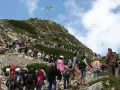 Tłum turystów podąża czerwonym szlakiem na Giewont. W oddali widoczny krzyż.