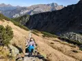 Osoba wędruje kamienistym szlakiem w Tatrach. Widok na góry i dolinę, idealne tatry szlaki dla średnio zaawansowanych.