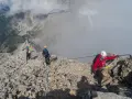 Grupa ludzi pokonuje ferraty, wspinając się po skalistym grzbiecie. Widok zapiera dech w piersiach, a chmury otulają szczyty.
