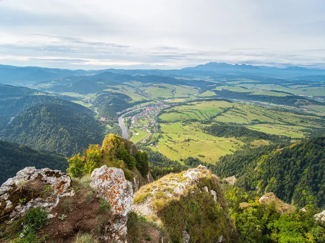 Widok z góry na dolinę z rzeką i miasteczkiem, w oddali majaczą Tatry. Widok przypomina trzy korony.