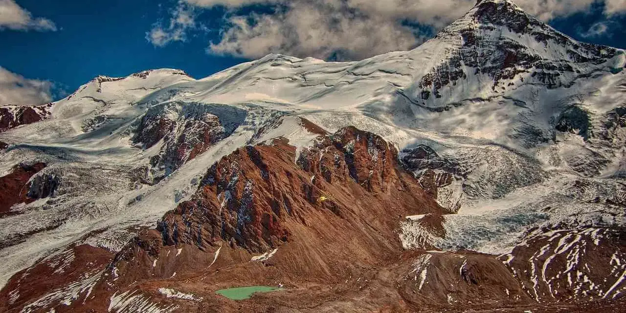 Aconcagua, najwyższy szczyt Ameryki, wznosi się majestatycznie, pokryty śniegiem i lodem. U jego stóp turkusowe jezioro.