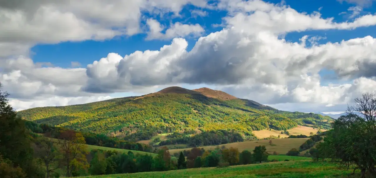 Bieszczady jakie to góry? Łagodne, zielone wzgórza pokryte lasami, z pojedynczymi szczytami i malowniczymi dolinami, pod błękitnym niebem z kłębiastymi chmurami.