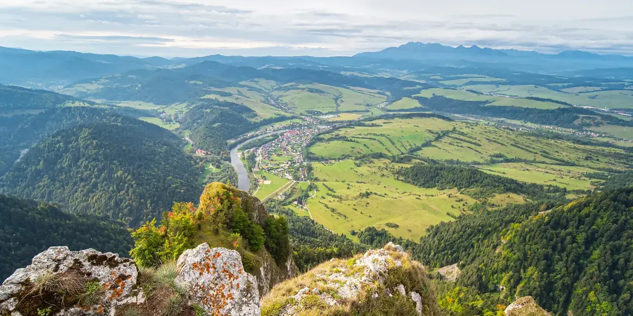 Widok z góry na dolinę z rzeką i miasteczkiem, w oddali majaczą Tatry. Widok przypomina trzy korony.