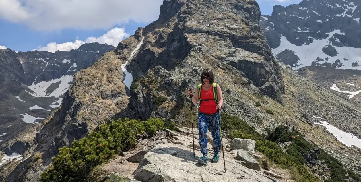 Kobieta z kijkami trekkingowymi na skalistej ścieżce w Tatrach. Czy to szlak dla każdego? Kościelec czeka!