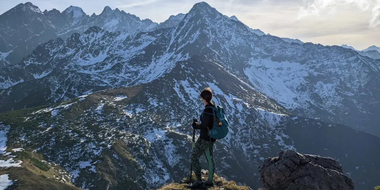 Osoba z plecakiem i kijkami podziwia zimowe Tatry Bielskie. Wspaniałe widoki na szlaki.