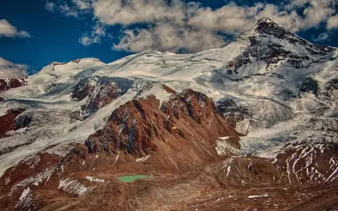 Aconcagua, najwyższy szczyt Ameryki, wznosi się majestatycznie, pokryty śniegiem i lodem. U jego stóp turkusowe jezioro.