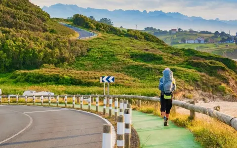 Pielgrzym z plecakiem idzie ścieżką wzdłuż wybrzeża, jedną z wielu tras Camino de Santiago.