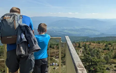 Ojciec i syn podziwiają widok z **Baraniej Góry**. W oddali widać pasma górskie i doliny.