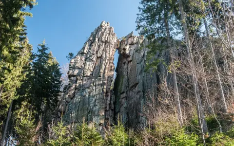 Skalny most na rudawych janowickich szlakach, otoczony drzewami.