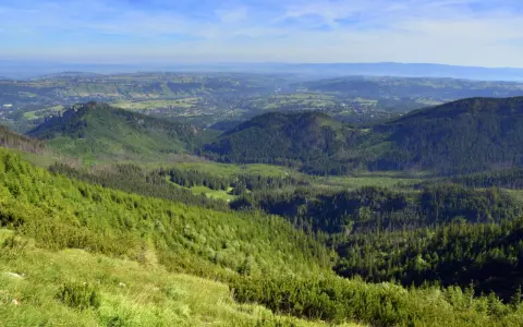 Widok z górskiego szczytu w Tatrach na zielone doliny i lasy.