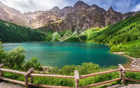 Turkusowe jezioro otoczone zielonymi zboczami gór i lasem, przypominające beskidzkie Morskie Oko.