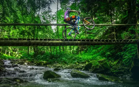 Rowerzysta wykonuje trik na drewnianym moście nad potokiem. Wspaniałe trasy rowerowe Zakopane czekają na odkrycie!