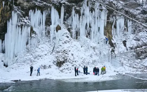 Lodowe wodospady w Rudawce Rymanowskiej zimową porą. Grupa ludzi obserwuje wspinaczkę lodową. Jak dojechać?