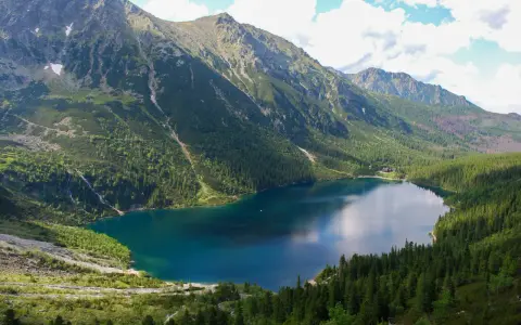 Największe jezioro w Tatrach, Morskie Oko, otoczone zielonymi lasami i skalistymi szczytami.