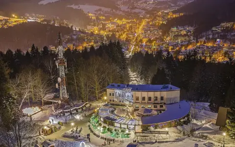 Góra Parkowa w Krynicy nocą, oświetlona choinka i budynek z tarasem widokowym. W tle rozświetlone miasto.