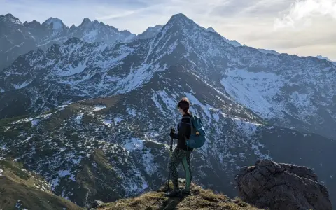 Osoba z plecakiem i kijkami podziwia zimowe Tatry Bielskie. Wspaniałe widoki na szlaki.