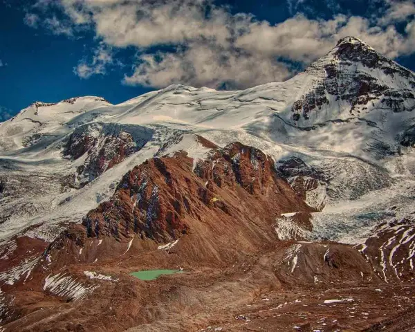 Aconcagua, najwyższy szczyt Ameryki, wznosi się majestatycznie, pokryty śniegiem i lodem. U jego stóp turkusowe jezioro.