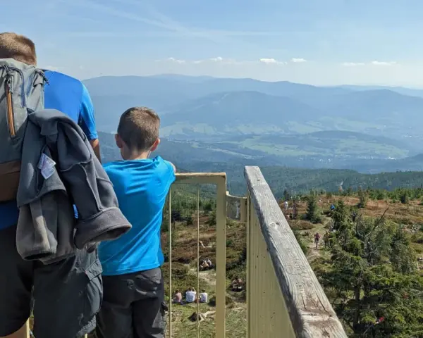 Ojciec i syn podziwiają widok z **Baraniej Góry**. W oddali widać pasma górskie i doliny.