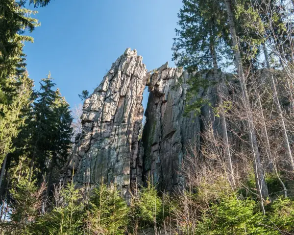 Skalny most na rudawych janowickich szlakach, otoczony drzewami.