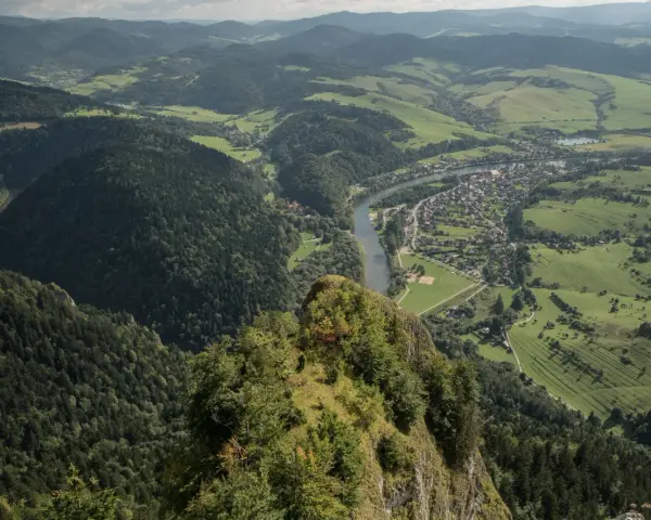 Widok z Trzech Koron na Szczawnicę i Dunajec. Góry Pieniny w zieleni, malownicza dolina rzeki i miasteczko.
