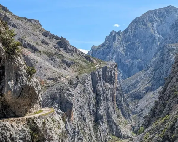 Wąska ścieżka wzdłuż skalnej ściany, część szlaku Ruta del Cares, prowadzi przez surowe, górskie krajobrazy.