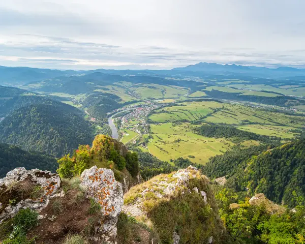 Widok z góry na dolinę z rzeką i miasteczkiem, w oddali majaczą Tatry. Widok przypomina trzy korony.
