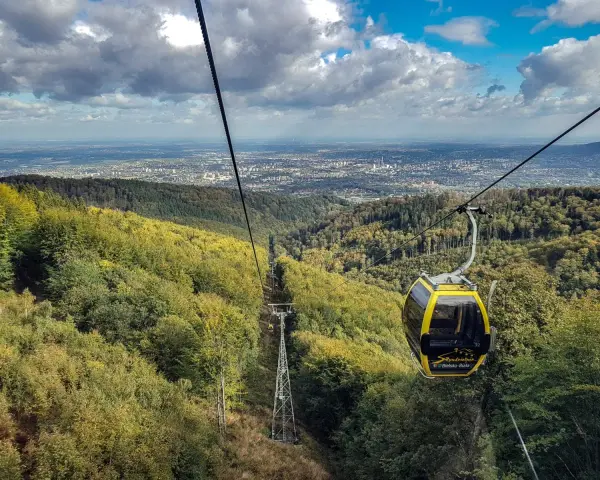 Kolejka linowa wjeżdża na szlak na Klimczok z Bielska, oferując widok na miasto i jesienne lasy.