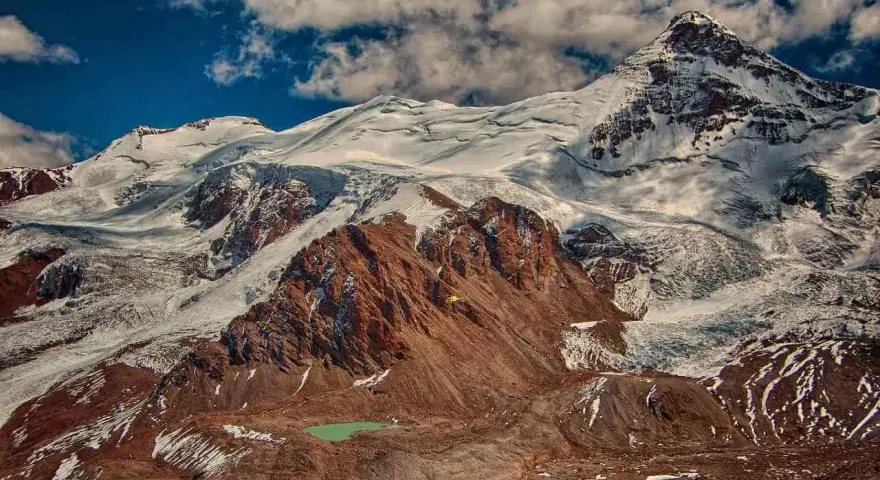Aconcagua, najwyższy szczyt Ameryki, wznosi się majestatycznie, pokryty śniegiem i lodem. U jego stóp turkusowe jezioro.
