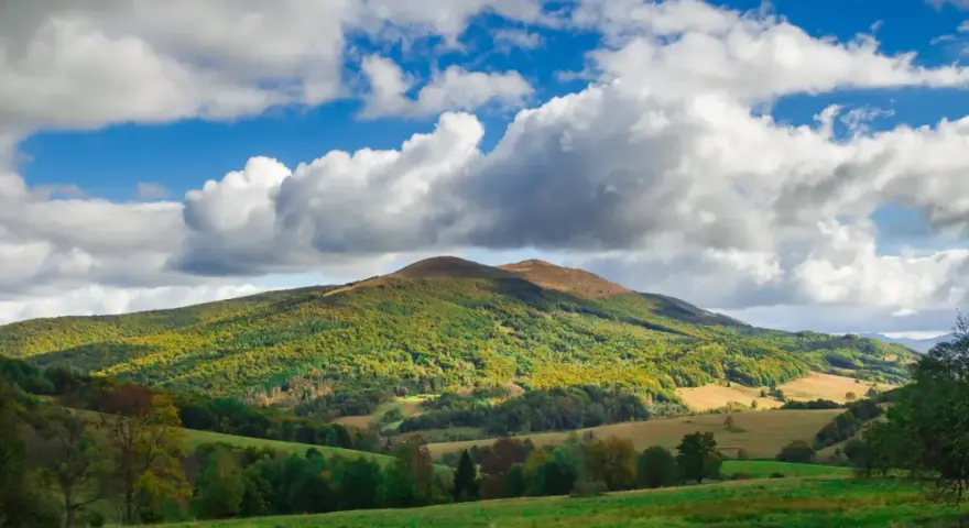 Bieszczady jakie to góry? Łagodne, zielone wzgórza pokryte lasami, z pojedynczymi szczytami i malowniczymi dolinami, pod błękitnym niebem z kłębiastymi chmurami.