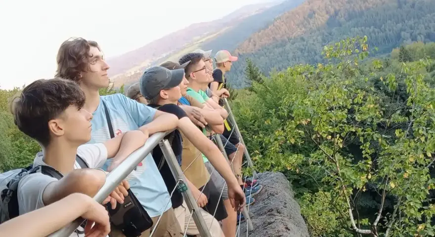 Grupa młodych ludzi na szlaku, podziwiająca widok. Idealne miejsce na pierwsze wyprawy trekkingowe dla początkujących.