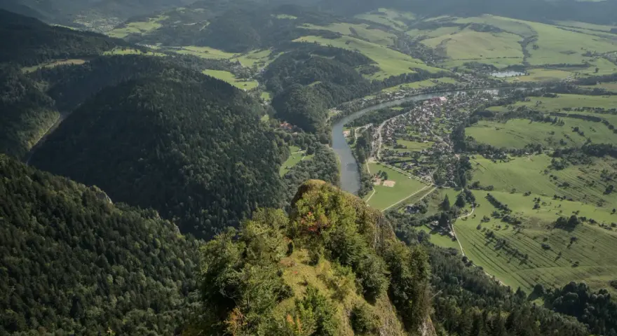Widok z Trzech Koron na Szczawnicę i Dunajec. Góry Pieniny w zieleni, malownicza dolina rzeki i miasteczko.