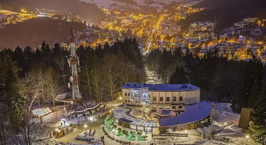 Góra Parkowa w Krynicy nocą, oświetlona choinka i budynek z tarasem widokowym. W tle rozświetlone miasto.