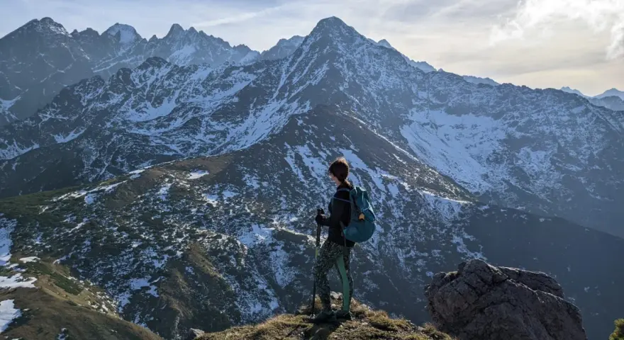 Osoba z plecakiem i kijkami podziwia zimowe Tatry Bielskie. Wspaniałe widoki na szlaki.