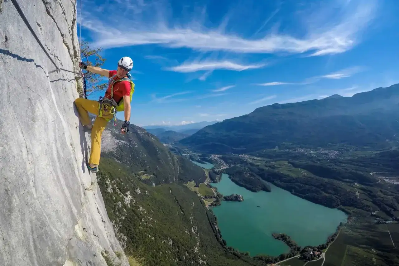Wspinacz na via ferrata Garda z widokiem na jezioro i g&oacute;ry.
