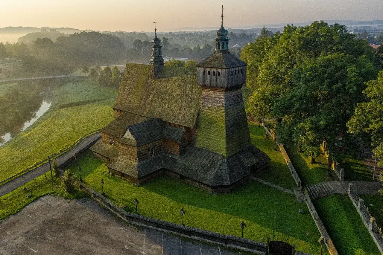 Drewniany kości&oacute;ł w Beskidzie Niskim, otoczony zielenią i mgłą o poranku. Piękno beskidzkich miejscowości.