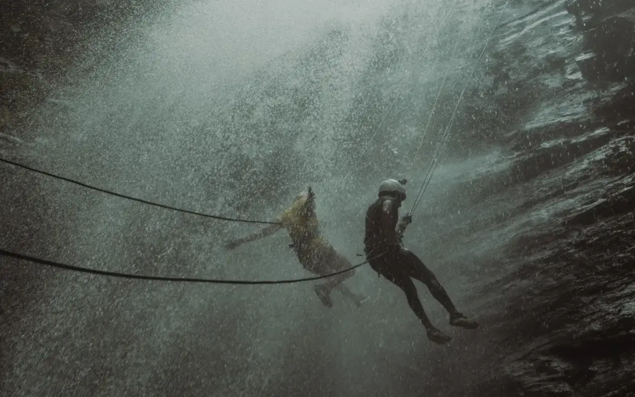 Dwóch ludzi zjeżdża na linach przez wodospad. To właśnie jest canyoning – ekstremalna przygoda!