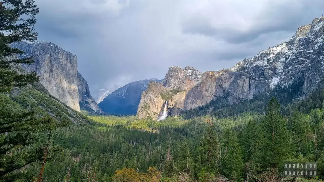 Majestatyczne góry i wodospad w parku narodowym Yosemite. Las sosnowy u podnóża skalnych ścian.